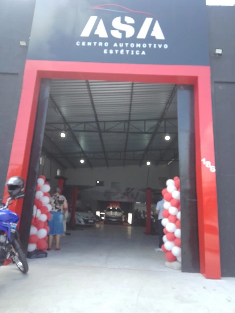 Entrada da ASA com o portal vermelho aberto e o galpão ao fundo