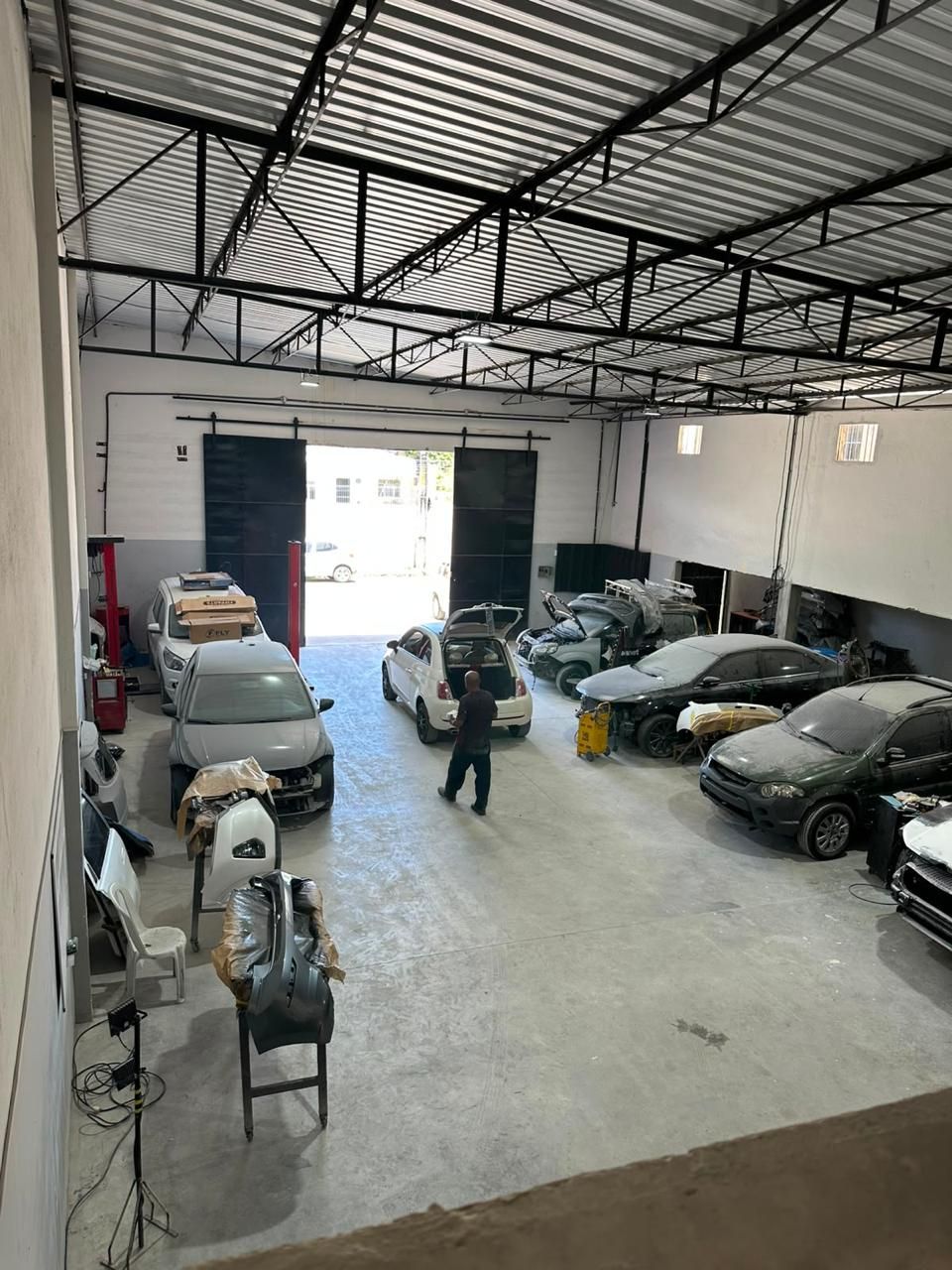 Galpão da ASA com carros em lanternagem e peças em preparação para pintura